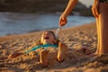 Child, tickling sibling on the beach on the feet with feather, kid cover in sand, smiling, laughing