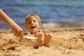 Child, tickling sibling on the beach on the feet with feather, kid cover in sand, smiling, laughing