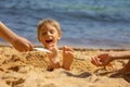 Child, tickling sibling on the beach on the feet with feather, kid cover in sand, smiling, laughing