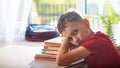 Home schooling, doing homework. the boy lay down wearily on a stack of books and textbooks. little boy student sitting at table Royalty Free Stock Photo