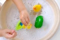 child, toddler 3 years old plays with rubber yellow duck for swimming, children's hand close-up, toy in soapy foam, concept Royalty Free Stock Photo