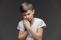 Child toothache. holding his cheek, dental pain. Closeup portrait boy with sensitive tooth. isolated grey wall background. Royalty Free Stock Photo