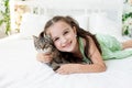 A child is torturing an animal, a little girl with a cat is lying on the bed, the concept of a child`s friendship with animals