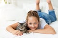 A child is torturing an animal, a little girl with a cat is lying on the bed, the concept of a child`s friendship with animals