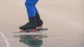 The child train on ice speed skating. The legs in skates close up. The kid girl skates in the winter in sportswear sport