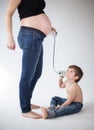 Child trying to listen inside the belly of a pregnant woman with a tin can phone Royalty Free Stock Photo