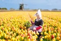 Child In Tulip Flower Field. Windmill In Holland