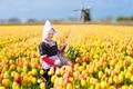 Child in tulip flower field. Windmill in Holland Royalty Free Stock Photo