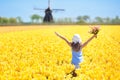 Kids in tulip flower field. Windmill in Holland