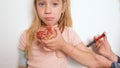 A child with type 1 diabetes eats a donut while her mother injects insulin into her arm. Little girl with diabetes