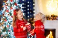 Child under Christmas tree at home. Little boy and girl in knitted sweater with Xmas ornament drink hot chocolate. Family with Royalty Free Stock Photo