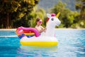 Child on unicorn float in swimming pool. Kids swim