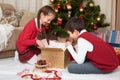 Child unpack gift boxes near christmas tree, decoration at home, happy emotion, winter holiday concept