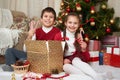 Child unpack gift boxes near christmas tree, decoration at home, happy emotion, winter holiday concept