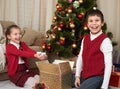 Child unpack gift boxes near christmas tree, show a handful of snow, decoration at home, happy emotion, winter holiday concept