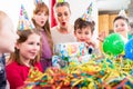 Child unwrapping birthday gift with friends