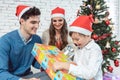 Child unwrapping Christmas present with his family