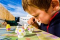 Child uses his free time as a hobby painting plaster pieces outdoors