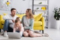 Child using laptop near excited parents