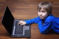 Child using laptop PC lying on wooden floor. Top view. Education, learning, technology concept Royalty Free Stock Photo