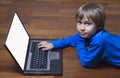 Child using laptop PC lying on wooden floor. Top view. Education, learning, technology concept Royalty Free Stock Photo