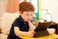 Child using tablet pc on bed at home. Cute boy on sofa is watching cartoon, playing games and learning from laptop. Education, fun Royalty Free Stock Photo