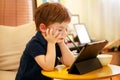 Child using tablet pc on bed at home. Cute boy on sofa is watching cartoon, playing games and learning from laptop. Education, fun Royalty Free Stock Photo