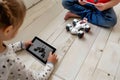 child using a tablet to control a robotic toy on the floor Royalty Free Stock Photo