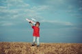 Child in the village with plane in his hands. Retro style airplane on nature background. Child boy toddler playing with Royalty Free Stock Photo