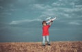 Child in the village with plane in his hands. Retro style airplane on nature background. Child boy toddler playing with Royalty Free Stock Photo