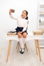 Child vlogger stream online. Child school uniform smart kid video conferencing while sit table. Girl holds smartphone Royalty Free Stock Photo