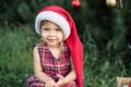 Child waiting for a Christmas in wood in juli. portrait of little children near christmas tree. girl decorating christmas tree Royalty Free Stock Photo