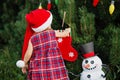 Child waiting for a Christmas in wood in juli. portrait of little children near christmas tree. girl decorating christmas tree Royalty Free Stock Photo