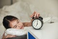 Child wakes up in the morning with alarm clock on bed Royalty Free Stock Photo