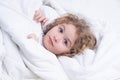 Child wakes up from sleep in bed. Kid wakes up in the morning in the bedroom. Royalty Free Stock Photo