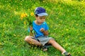 Child walk in the field with dandelions on a clear spring or summer day