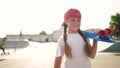child walk with a skateboard. girl in a red cap with a skateboard on the playground portrait. skateboarder child walk