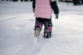 Child walks through snowdrift. Rear view of little girl in pink winter jacket walking along snowy road in park after Royalty Free Stock Photo