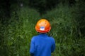 The child walks in the wild forest.  The boy got lost on the hike.  A child in a helmet is looking for a way. Royalty Free Stock Photo