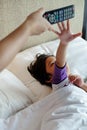 Asian Child On Bed Wants to Take Over Television Remote Control from His Parent Hands. Addiction Concept Royalty Free Stock Photo