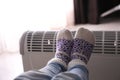 Child warming feet on electric heater at home, closeup