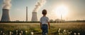 Child watches smoke coming out of the chimney and cooling tower of a power plant