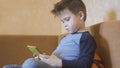 Child watching a movie on mobile phone. Bored boy home alone. Concept of quarantine and self-isolation Royalty Free Stock Photo