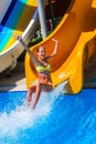 Child on water slide at aquapark show thumb up.