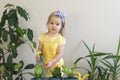 Funny little girl gardener with plants in the room at home. Royalty Free Stock Photo