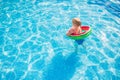 Child with watermelon inflatable ring in swimming pool. Little girl learning to swim in outdoor pool. Water toys and floats for