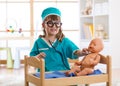 Child plays doctor with baby doll in nursery Royalty Free Stock Photo