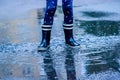 Child wearing blue rain boots jumping in puddles after rain. Childhood, laisure, happiness concept Royalty Free Stock Photo