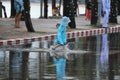 Child wearing blue raincoat walking on flood