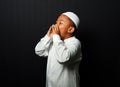 A child wearing a cap and koko screaming with hand in mouth isolated on black background